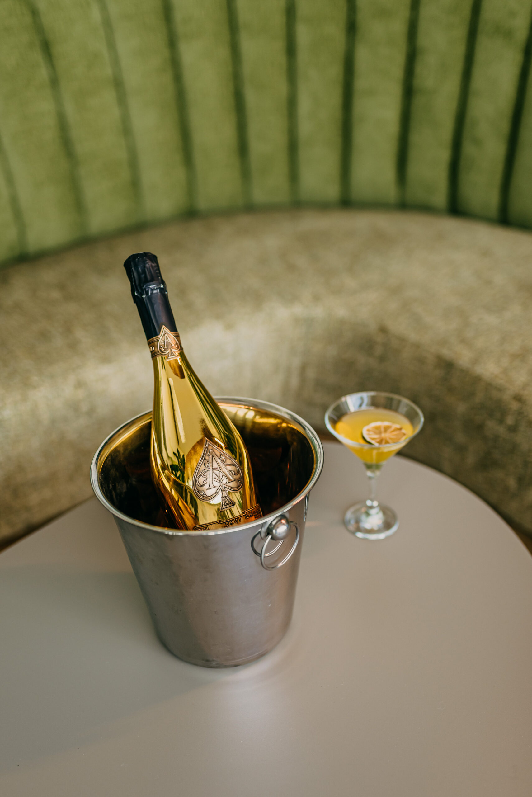 Armand de Brignac pezsgő és elegáns koktél egy asztalon, zöld bársony háttérrel Show Dinner