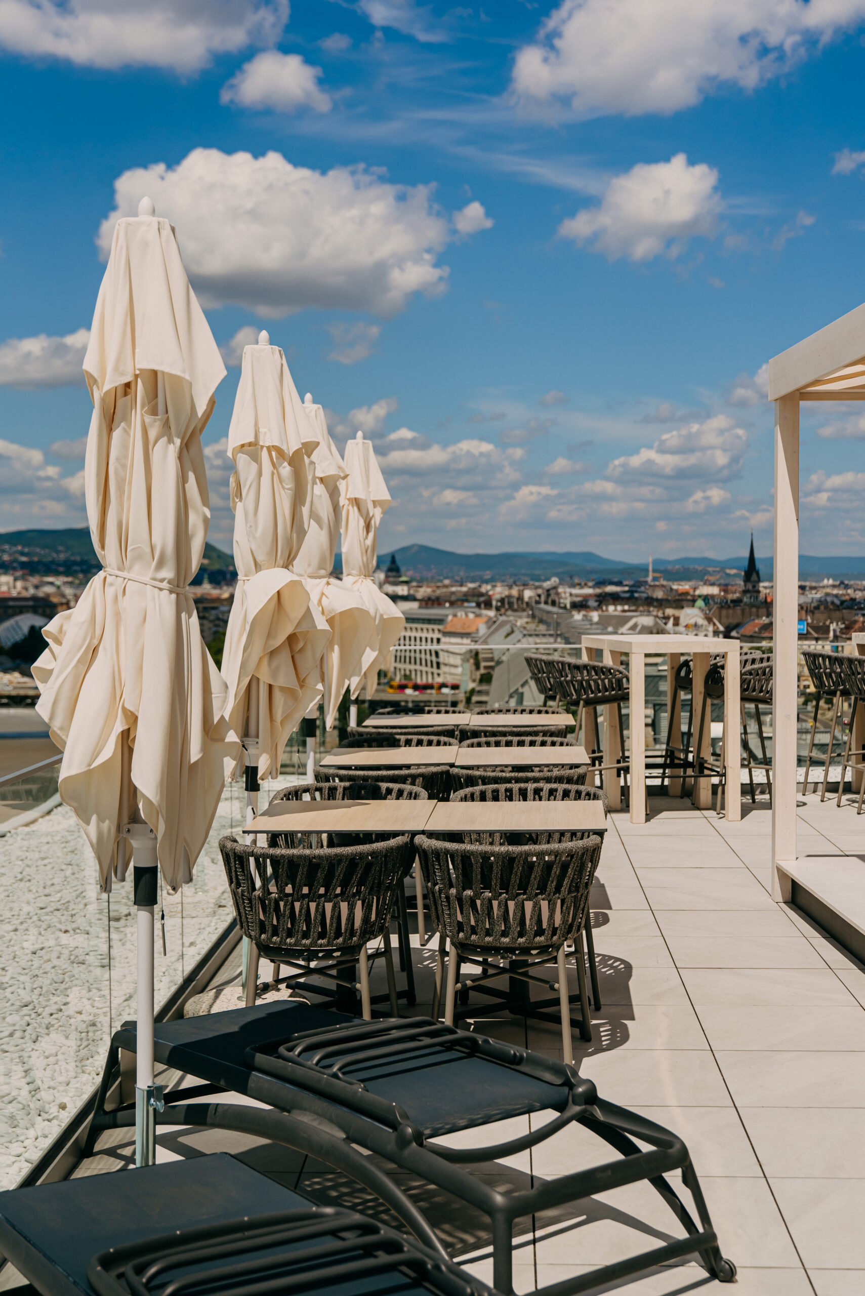 Rooftop terasz elegáns kültéri bútorokkal és napernyőkkel, panorámás kilátással Budapestre a Selva Skybarból